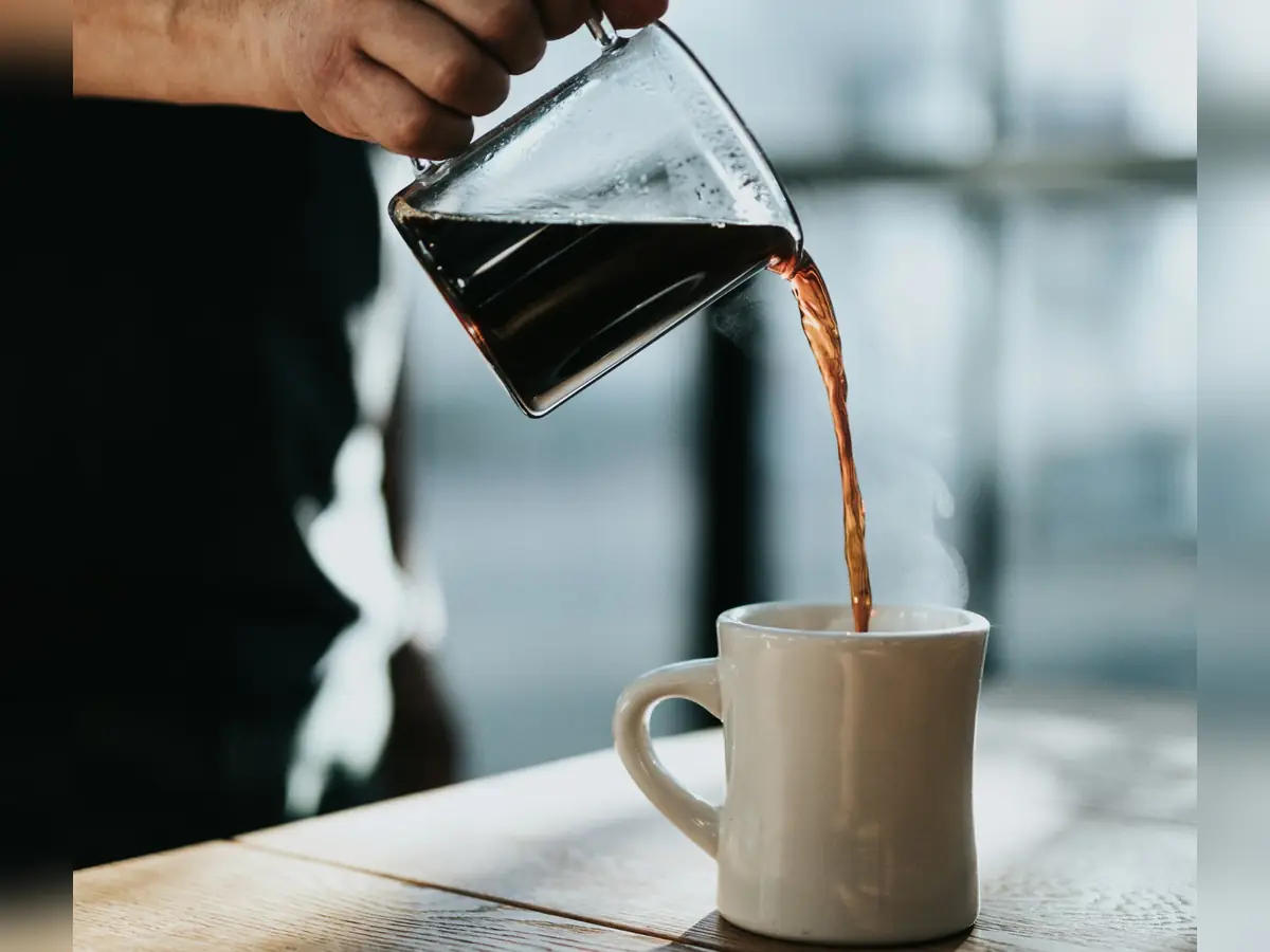 Freshly brewed coffee poured into a cup on a wooden table
